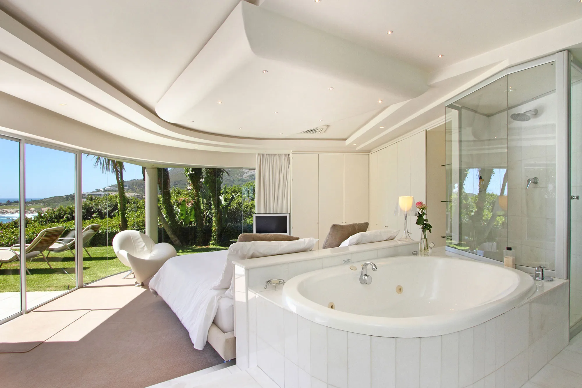Modern bedroom with large windows bathtub and garden view