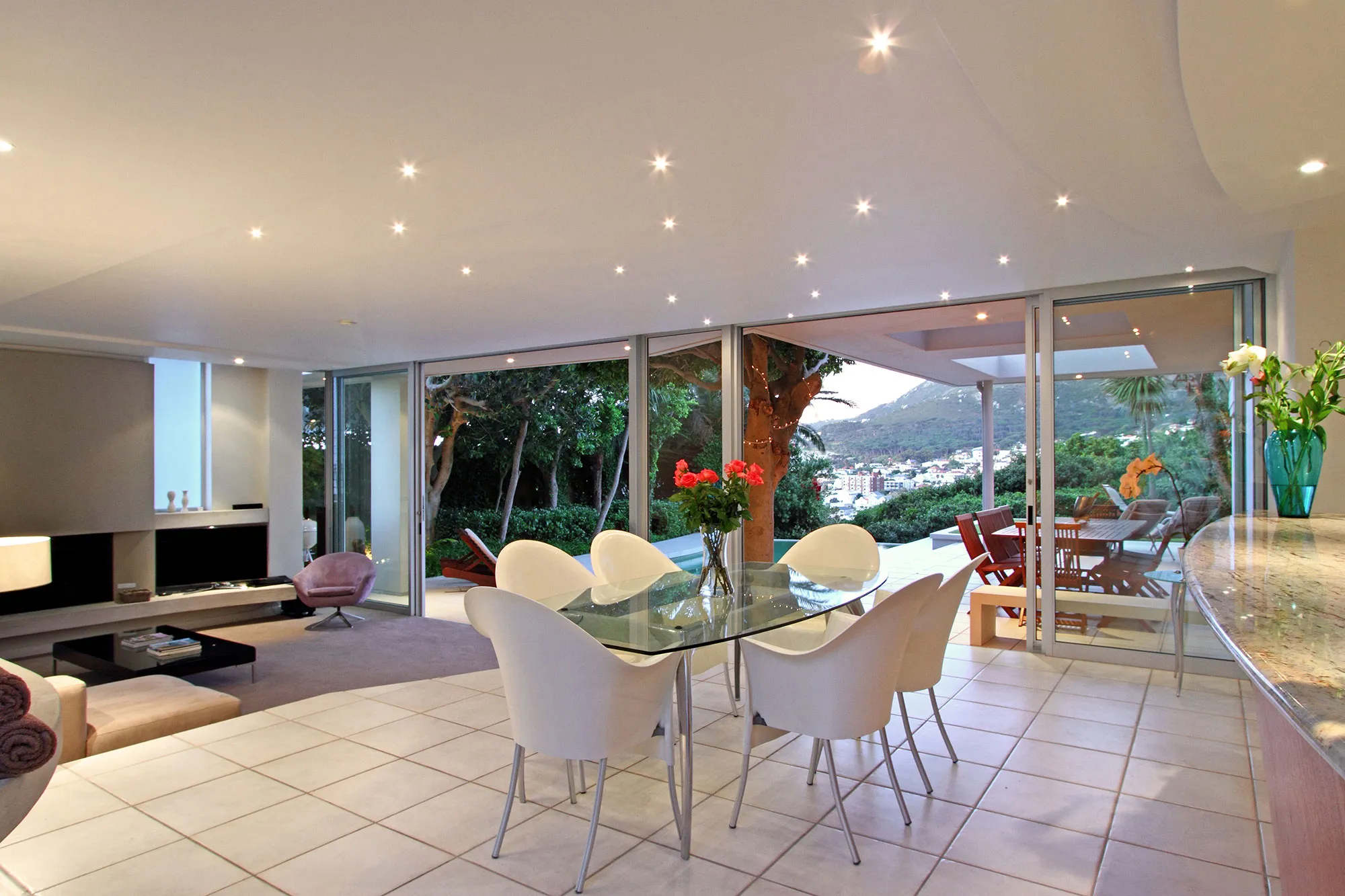 Modern dining area with glass table white chairs and view of outdoor patio