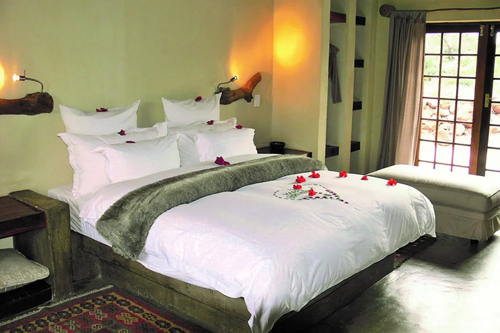 Cozy bedroom with a large bed decorated with rose petals and plush pillows