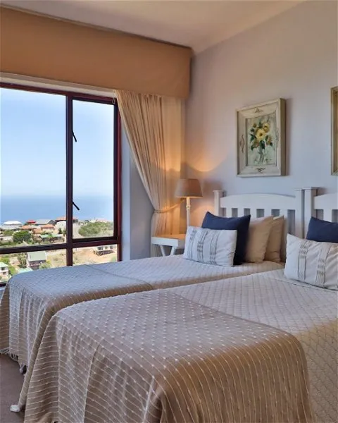 Two beds in a bedroom with a large window and ocean view