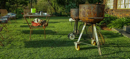 Rusty metal braai stands on a grassy lawn with outdoor furniture