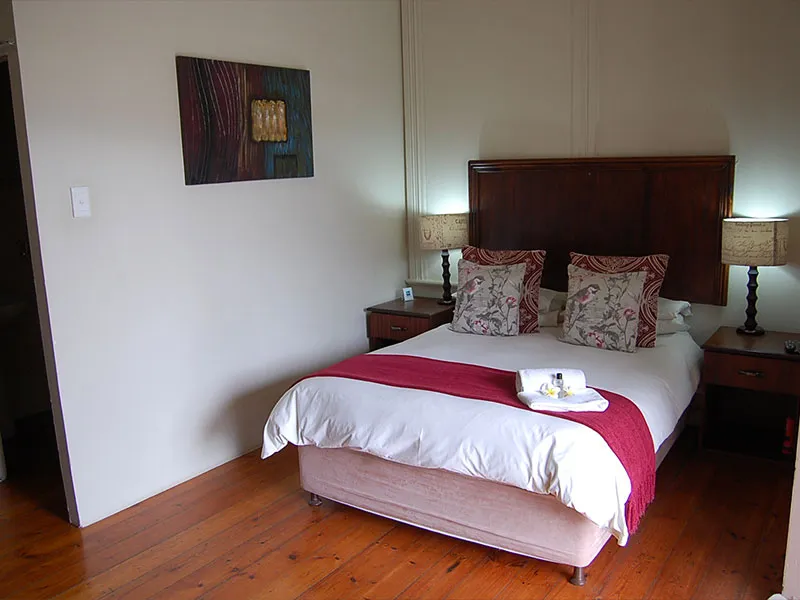 Neat bedroom with a double bed wooden headboard and bedside tables with lamps