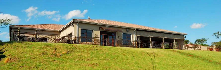 Modern house with large windows on a grassy hill under a blue sky