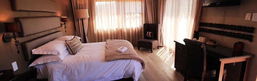 Cozy bedroom with a large bed armchair desk and natural light