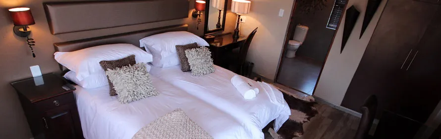 Hotel room with two beds bedside tables lamps and a desk