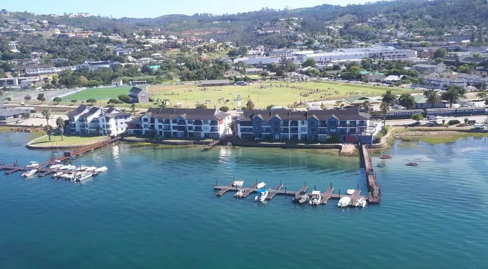 Aerial view of waterfront buildings with docks and boats surrounded by greenery