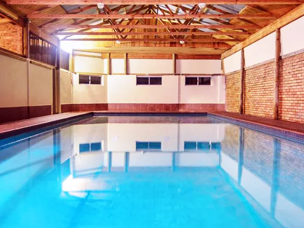 Indoor swimming pool with wooden ceiling and brick walls